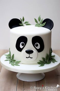 a panda bear cake with green leaves on it's head and eyes, sitting on a white plate