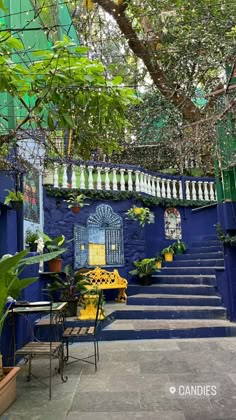 an outdoor patio with blue walls and steps leading up to the front door, surrounded by potted plants