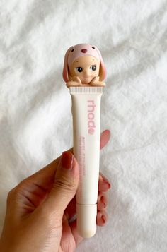 a person holding a toothbrush with a doll on it's head in their hand