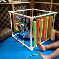 a man sitting on the floor next to an array of colorful candles and beads in a cage