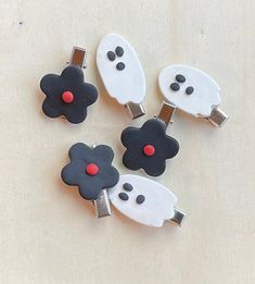 four black and white hair clips with red eyes, nose and mouth decorations on them