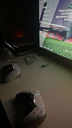 two video game controllers sitting on top of a table next to a tv screen and remote control