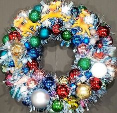 a christmas wreath hanging on the wall with ornaments and decorations around it's edges