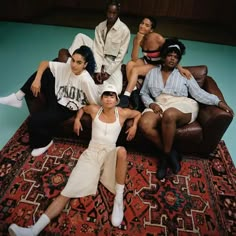 a group of people sitting on top of a rug in front of a blue wall