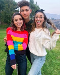 two young people standing next to each other on a field with trees in the background