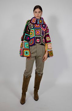 a woman standing in front of a white background wearing a colorful jacket and pants with multicolored crochet