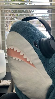 a stuffed shark with headphones on sitting in front of a window