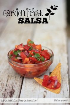 a glass bowl filled with salsa sitting on top of a wooden table