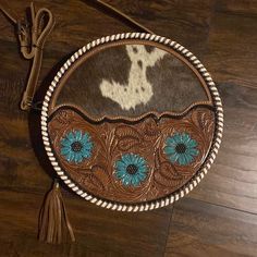 a brown and white cowhide purse with blue daisies on it's side