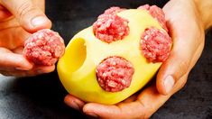 two hands holding a yellow object with meatballs on it