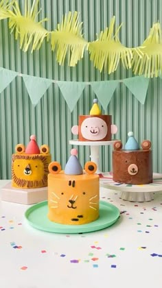 a table topped with cakes and cupcakes covered in fondant animal faces on top of cake stands