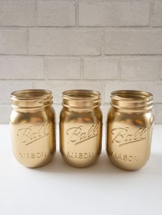 three gold mason jars sitting next to each other