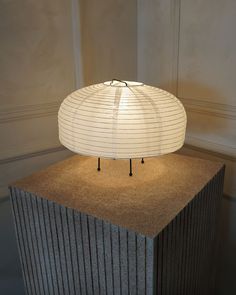 a lamp that is sitting on top of a block of concrete in front of a wall