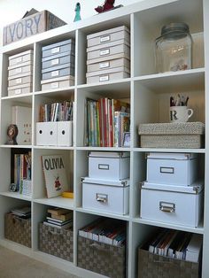 a book shelf filled with lots of books next to boxes and bins on top of it