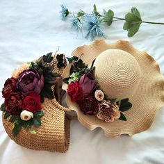 two hats with flowers on them laying on a bed