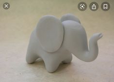 a white elephant figurine sitting on top of a table next to a wall