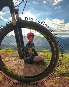 a man sitting on the ground next to a bike with words written in front of him