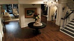 a living room filled with furniture and a chandelier hanging from the ceiling next to a staircase