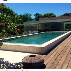 a large rectangular swimming pool in the middle of a wooden deck