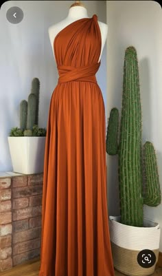 an orange dress sitting on top of a wooden floor next to cacti and succulents