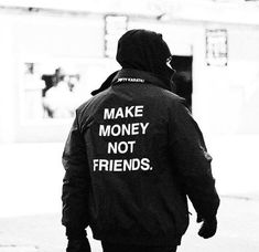 a man walking down the street wearing a jacket that says make money, not friends