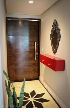 a modern entry way with a wooden door and decorative tile on the floor next to a plant