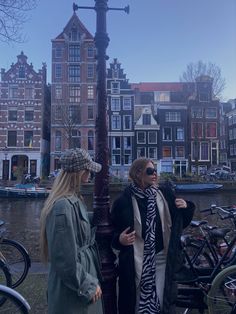 two women standing next to each other near a street light with bicycles in the background