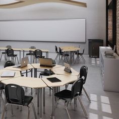 an empty classroom with desks and chairs in front of a whiteboard on the wall