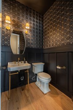 a bathroom with a toilet, sink and mirror next to each other on a wooden floor