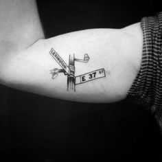 a black and white photo of a person's arm with a street sign tattoo on it