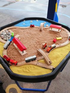 a child's play table with cars and trucks in the sand