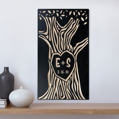 a black and gold tree with initials in the shape of a heart is displayed on a shelf