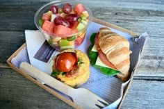 an open faced sandwich and fruit salad on a tray