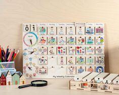 a wooden calendar sitting on top of a desk next to some pencils and markers