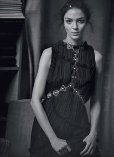 a black and white photo of a woman in a dress with beads on her neck