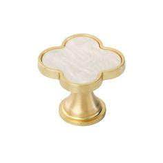 an image of a golden cabinet knob with white flower design on the front and bottom