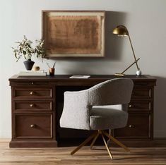 a chair sitting in front of a desk with a painting on the wall behind it