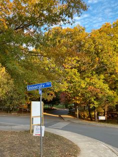 a blue street sign sitting on the side of a road next to a tree filled forest