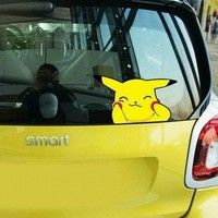 the rear window of a yellow car with a cartoon pikachu sticker on it