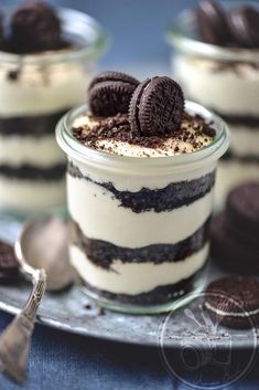 an oreo cookie and cream dessert in a glass jar with spoons on the side