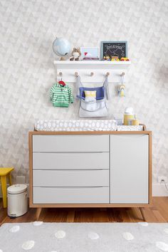 a baby's room with white furniture and geometric wallpaper