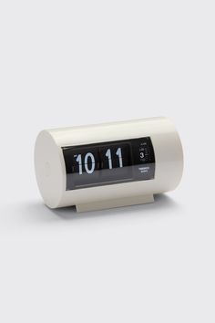 an alarm clock with the time 10 11 on it's face and white base