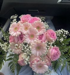 a bouquet of pink and white flowers sitting on top of a blue table cloth in the back seat of a car