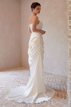 a woman in a white wedding dress standing on a brick floor