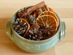 a bowl filled with orange slices, cinnamon and star anise on top of a wooden table