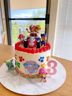 a birthday cake is decorated with paw patrol figures on top of the frosted cake