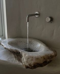 a stone sink with a faucet and water running from the faucet