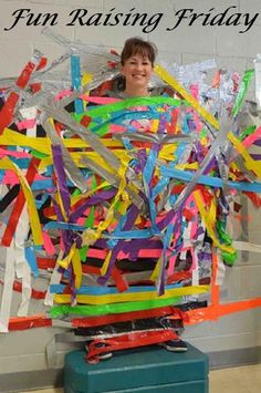 a young man standing in front of a sculpture made out of colorful strips of paper