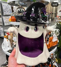 a hand holding up a halloween decoration with purple eyes and mouth wearing a witches hat