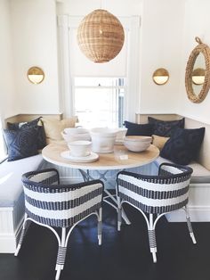 two chairs and a table with bowls on it in a room that has white walls